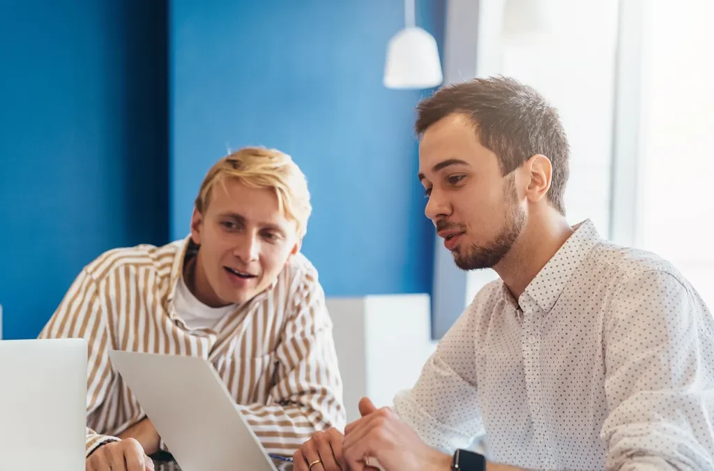 Cómo elegir agencia de Google Ads: 9 preguntas antes de firmar 5 Empresario revisando en el portátil una propuesta con un consultor de marketing antes de elegir agencia de Google Ads