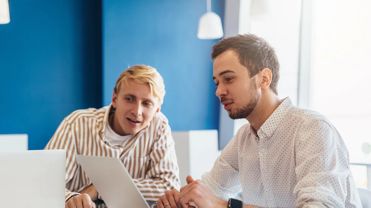Cómo elegir agencia de Google Ads: 9 preguntas antes de firmar 2 Empresario revisando en el portátil una propuesta con un consultor de marketing antes de elegir agencia de Google Ads