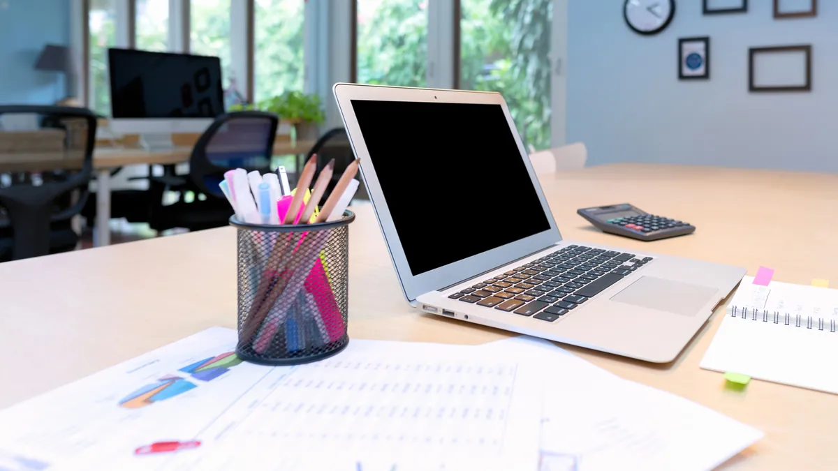 Portátil sobre una mesa de oficina con gráficos de rendimiento: calcular cuánto cuesta Google Ads para una PYME