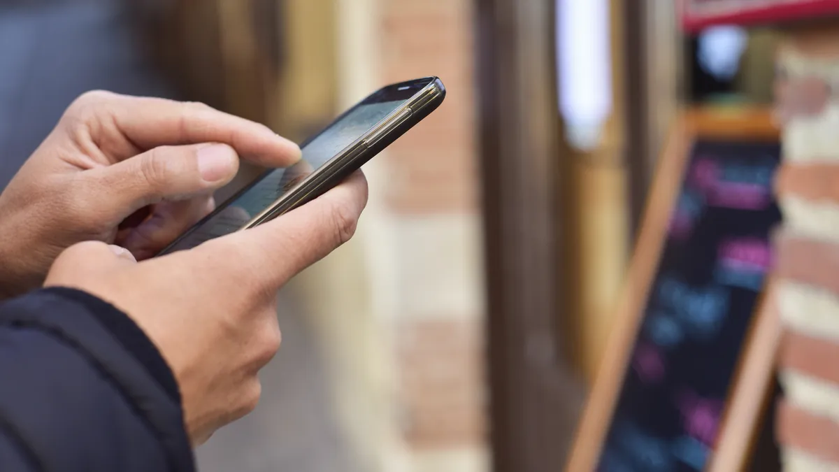 Desinformación e IA: cómo proteger la reputación de tu pyme 2 Persona consultando reseñas en el móvil: reputación online y desinformación para pymes