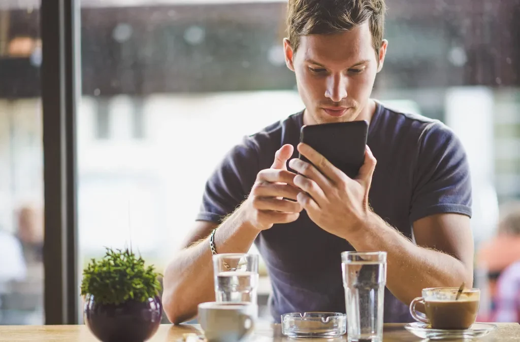 SEO para restaurantes: cómo llenar mesas desde Google 5 Cliente buscando restaurante en el móvil sentado en una terraza: SEO para restaurantes